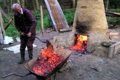 Removing hot charcoal from the bottom of the furnace.