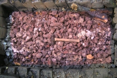 The ore being roasted in a wood-fuelled hearth to convert to the oxide [maghemite, Fe2O3], a magnetic form that is attracted to a magnet; a useful characteristic for checking that pieces are really iron ore. When roasted, the ore changes colour from grey to reddish-purple.